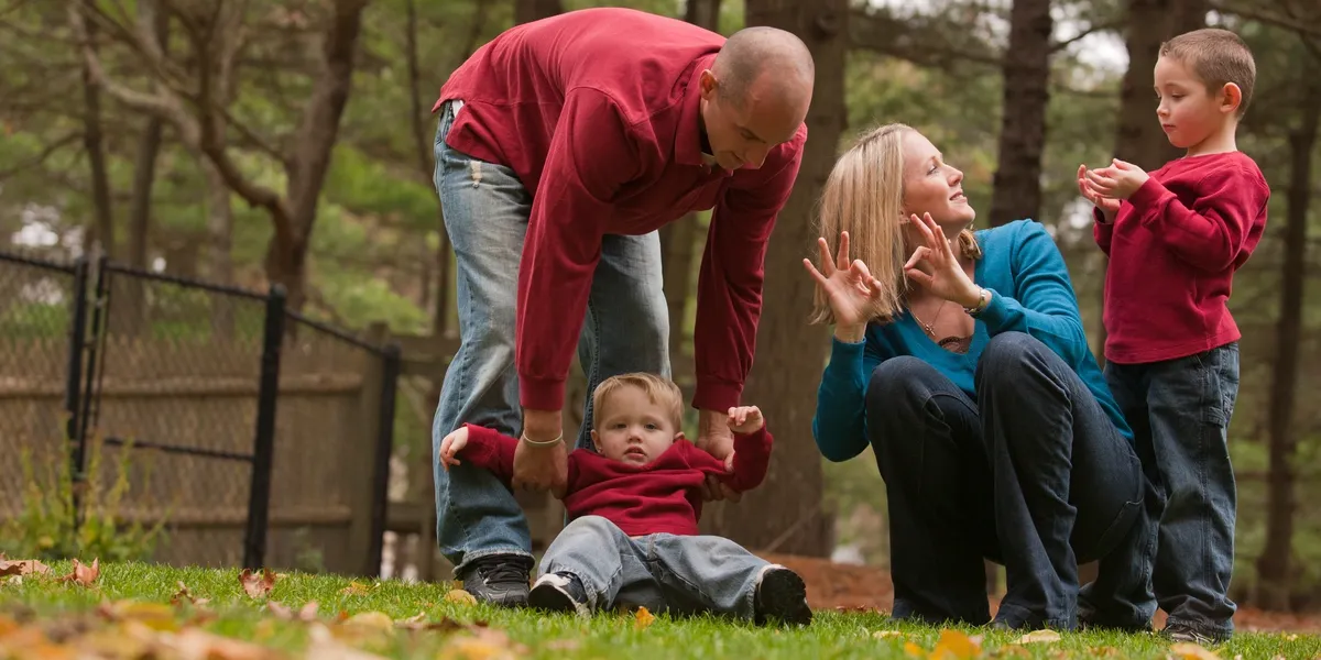 A man and woman playing with a child in the grass.