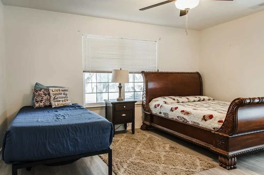 A bedroom with two beds and a nightstand.