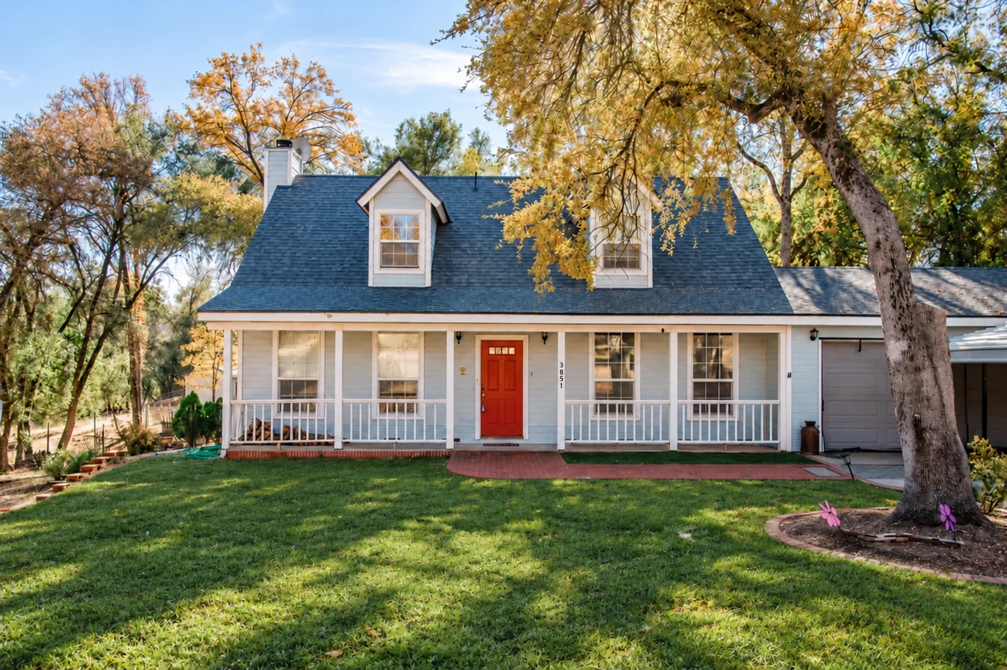 A white house with red door and blue shutters.